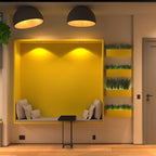 Two black Clérachic dome ceiling lights lit warm above a yellow wall niche with a cushioned bench and small planters.