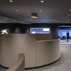 A single dark Clérachic dome ceiling light under a black ceiling dotted with spotlights, above a curved grey reception desk.