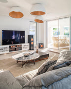 Three white Clérachic dome ceiling lights at different heights in a living room with a marble coffee table and a large grey sofa.