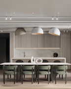 Three white and pale grey Clérachic dome ceiling lights in a row over a long white table with green dining chairs.