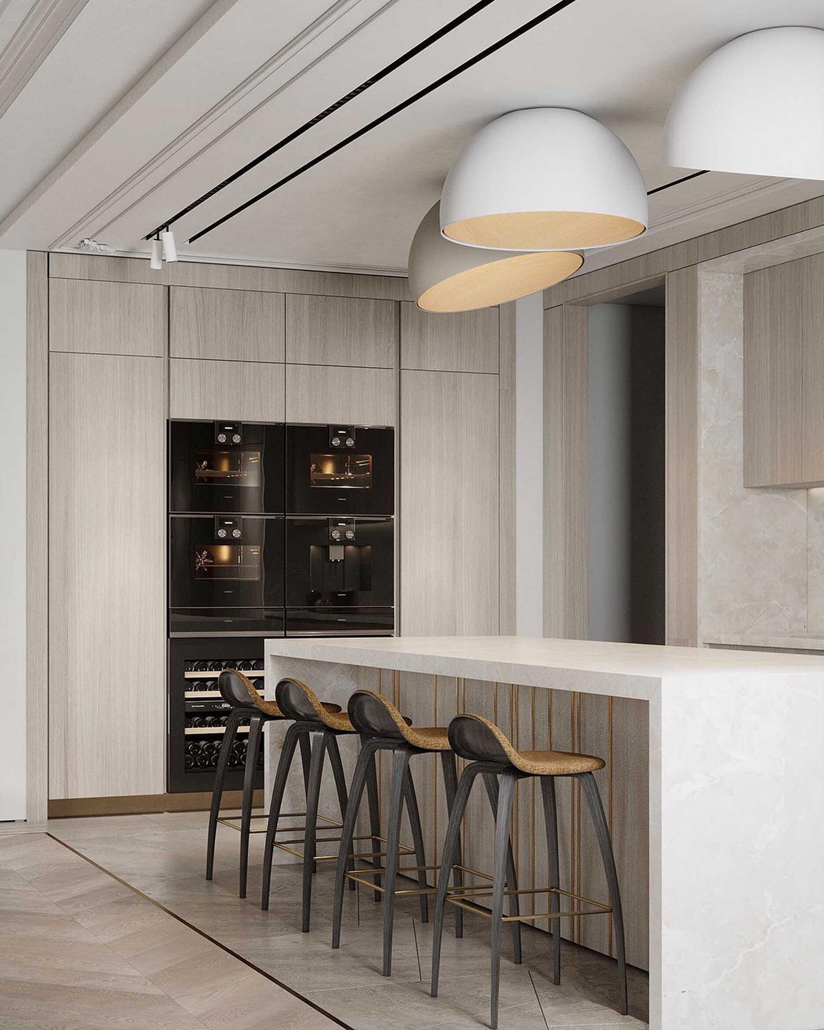 White Clérachic dome ceiling lights angled over a kitchen with tall oak cabinets, black ovens and a marble island with bar stools.