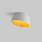 Grey-white Clérachic dome ceiling light tilted toward the camera on a light grey backdrop, its warm wood-effect interior in view.