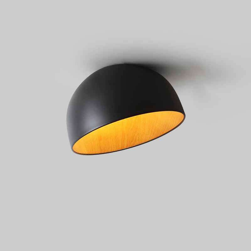 Black Clérachic dome ceiling light on a grey backdrop, tilted so that the golden wood-effect interior shows beneath the rim.
