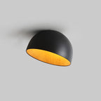 Black Clérachic dome ceiling light turned toward the camera on a grey backdrop, with a yellow-toned wood interior.