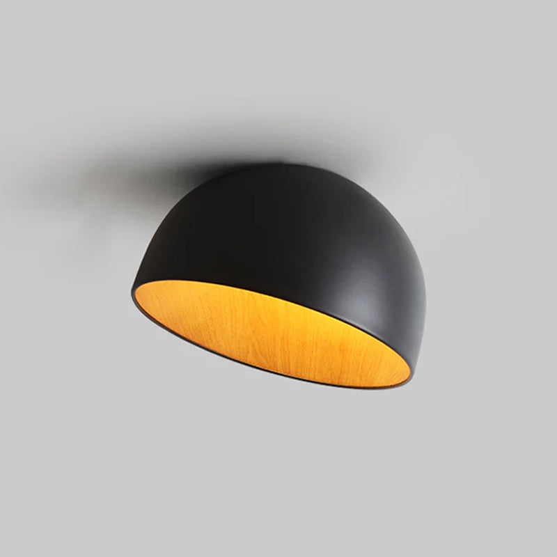 Black Clérachic dome ceiling light on a grey backdrop, tilted to show the glowing yellow wood-effect interior and the black rim.