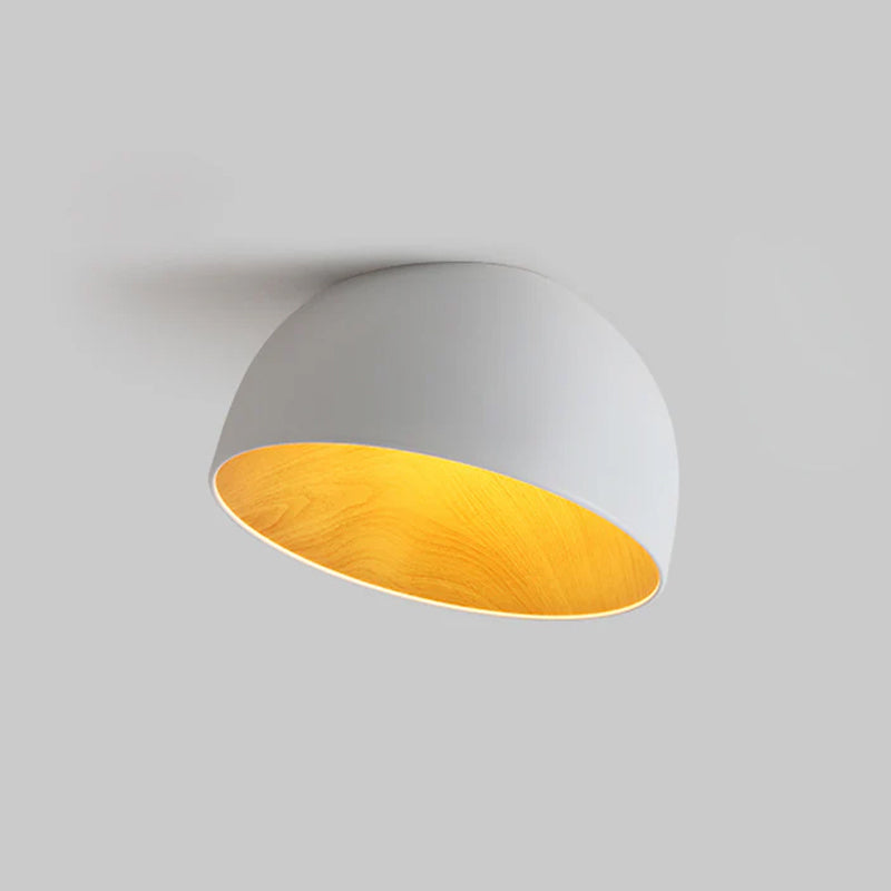 White Clérachic dome ceiling light with a golden wood-effect interior, tilted on a light grey backdrop with a soft shadow behind.