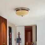 Unlit Clérachic dome ceiling light with a chrome trim ring, seen high above a hallway with slatted wooden doors and a coat stand.