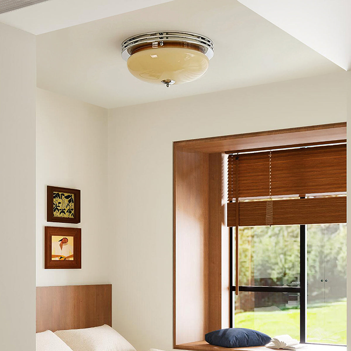 A Clérachic dome ceiling light with chrome trim above a bedroom with a wood-framed window seat and framed prints on the wall.