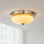 Lit from within, this Clérachic chrome-ringed dome light gives a warm amber glow against a white ceiling and sheer curtains.