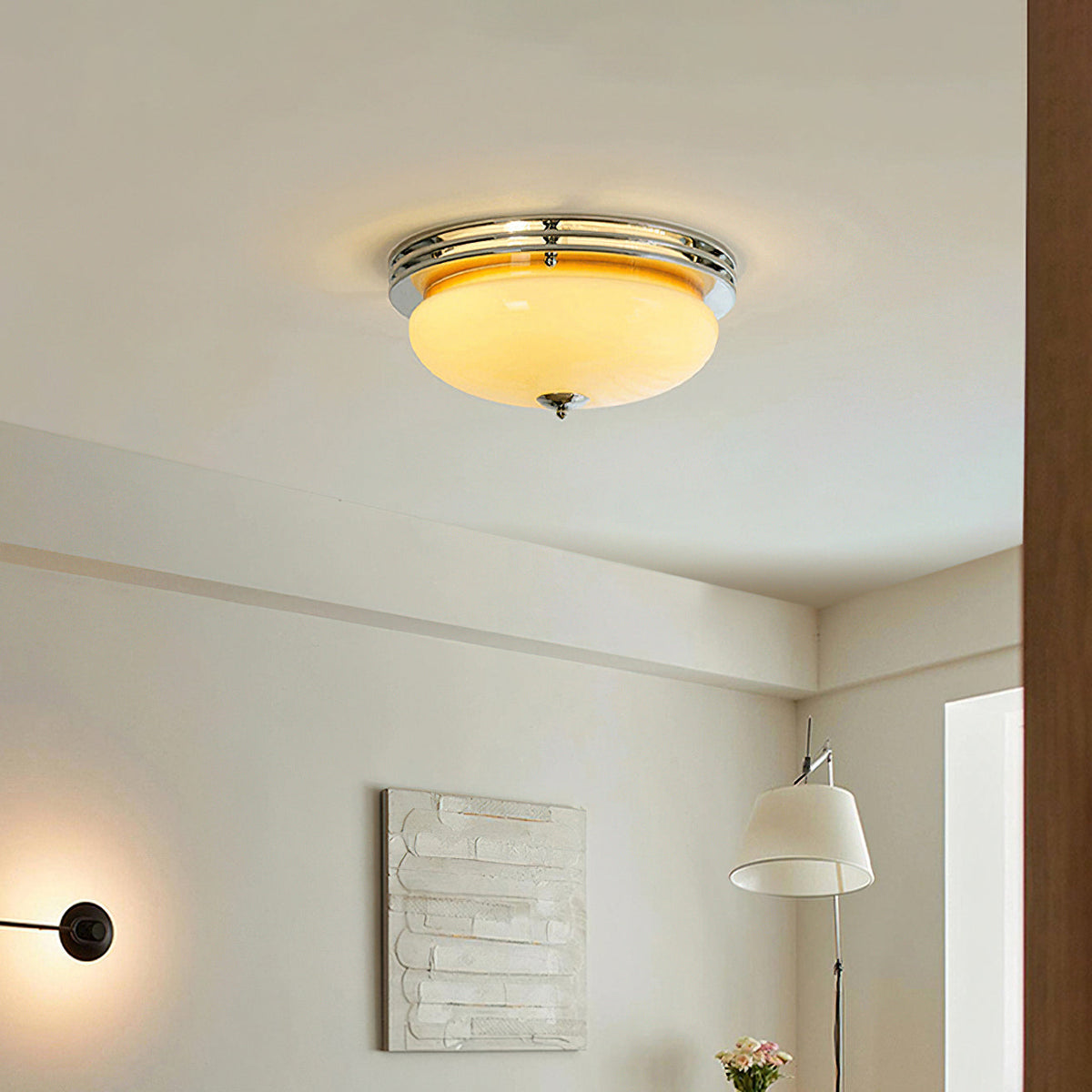 Warm light spreads from this Clérachic flush-mount dome over a white room with a textured art panel, a floor lamp and a wall light.