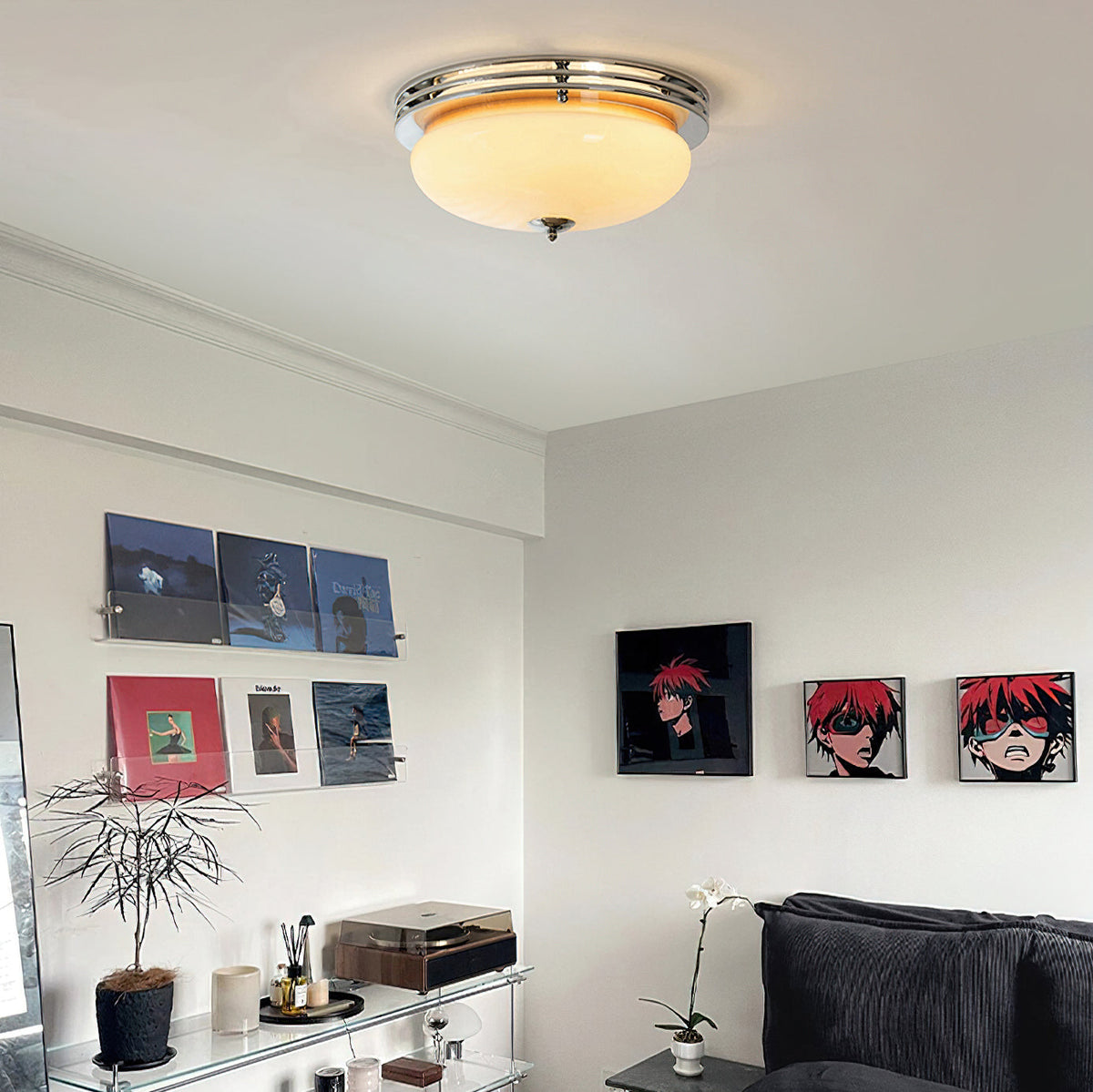 Living room with a Clérachic dome ceiling light above a record shelf, framed prints, a plant and a grey sofa.