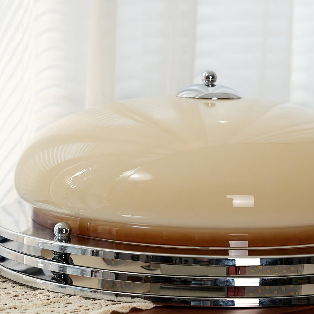 Low side view of this Clérachic ceiling light on a lace runner, showing the beige dome, chrome finial and stacked rings.