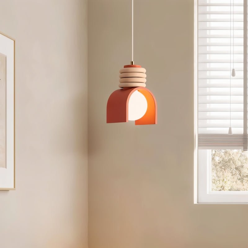 Clérachic pendant light in orange hanging in a corner of a cream room beside a window with white slatted blinds