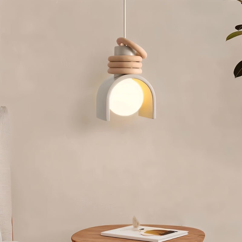 Clérachic pendant light in white hung above a round wooden side table and a book, its glowing orb framed by the arch