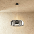 Clérachic wide smoked glass dome pendant on a slim black cord, lit from within, against a limewash wall.