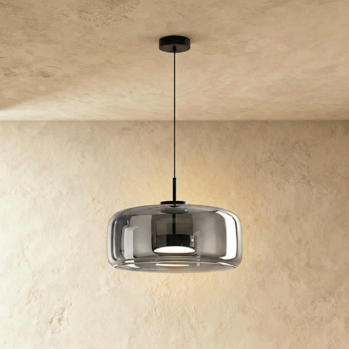 Clérachic wide smoked glass dome pendant on a slim black cord, lit from within, against a limewash wall.