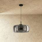 Clérachic wide smoked glass dome pendant switched off, black canopy and cord, against a textured limewash wall.