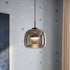 Clérachic close view of the rounded smoked glass pendant with a glowing disc diffuser, hung against pale blue wallpaper.