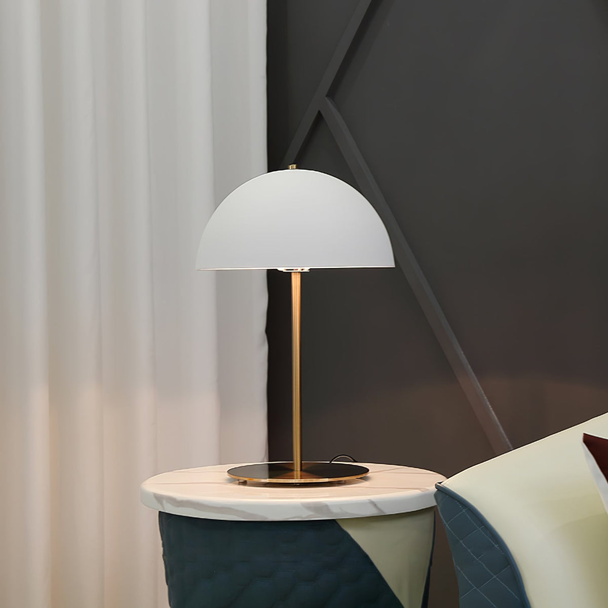 White dome lamp from Clérachic on a round brass base, on a marble side table next to soft white curtains.