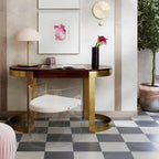 Closer crop of the pink Clérachic table lamp on a wood console, with a red bloom and a brass-framed chair below.