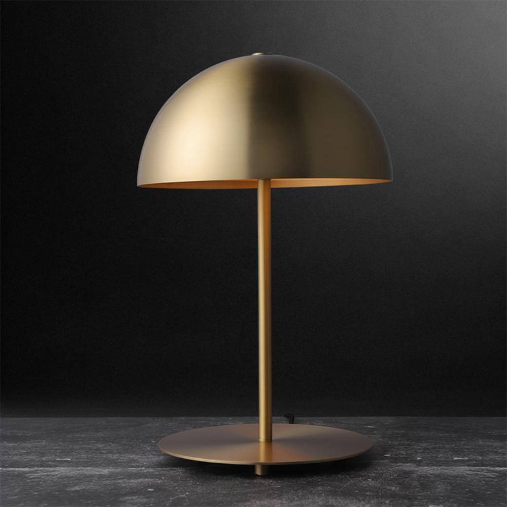Gold dome table lamp from Clérachic against a near-black backdrop, with a slim brass stem and a broad round base.