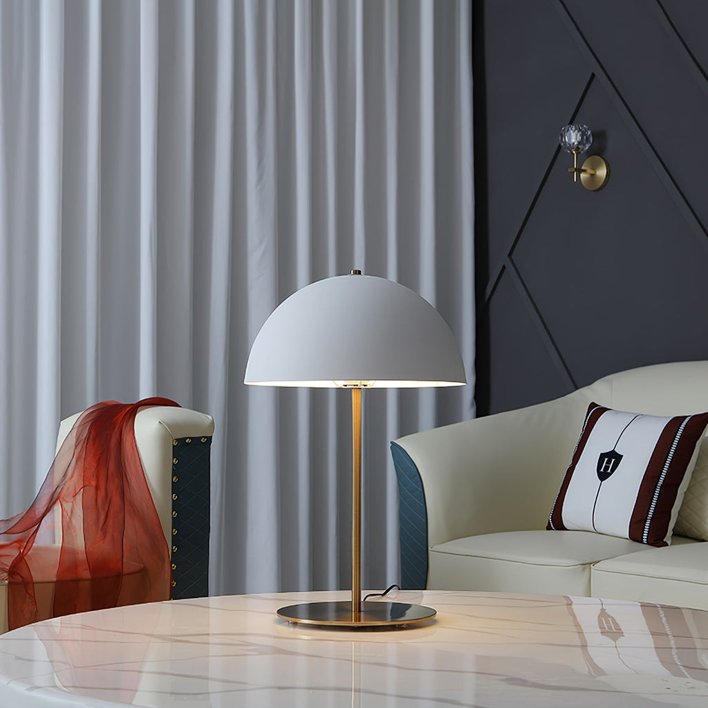 White dome table lamp from Clérachic on a marble table, with a cream sofa, striped cushion and grey curtains behind.
