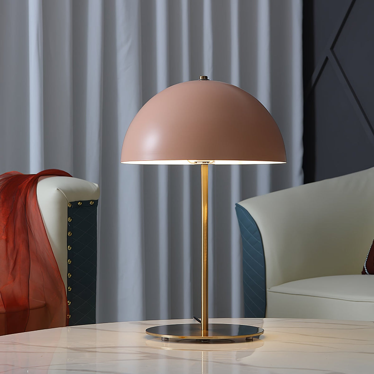 Pink dome table lamp from Clérachic on a marble surface, between a teal-and-cream sofa and a red throw.
