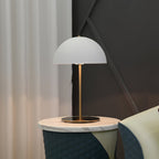 Clérachic dome table lamp in white on a marble-topped stool, with curtains and a teal quilted seat behind it.