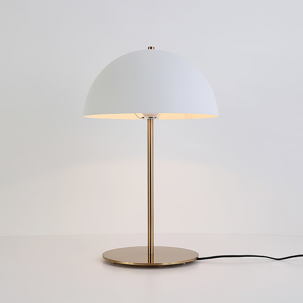 Lit white dome table lamp from Clérachic on a pale surface, with a black cord and a plain light-grey backdrop.