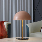 Pink dome lamp from Clérachic on a marble table, set against grey curtains with a cream armchair and red fabric.