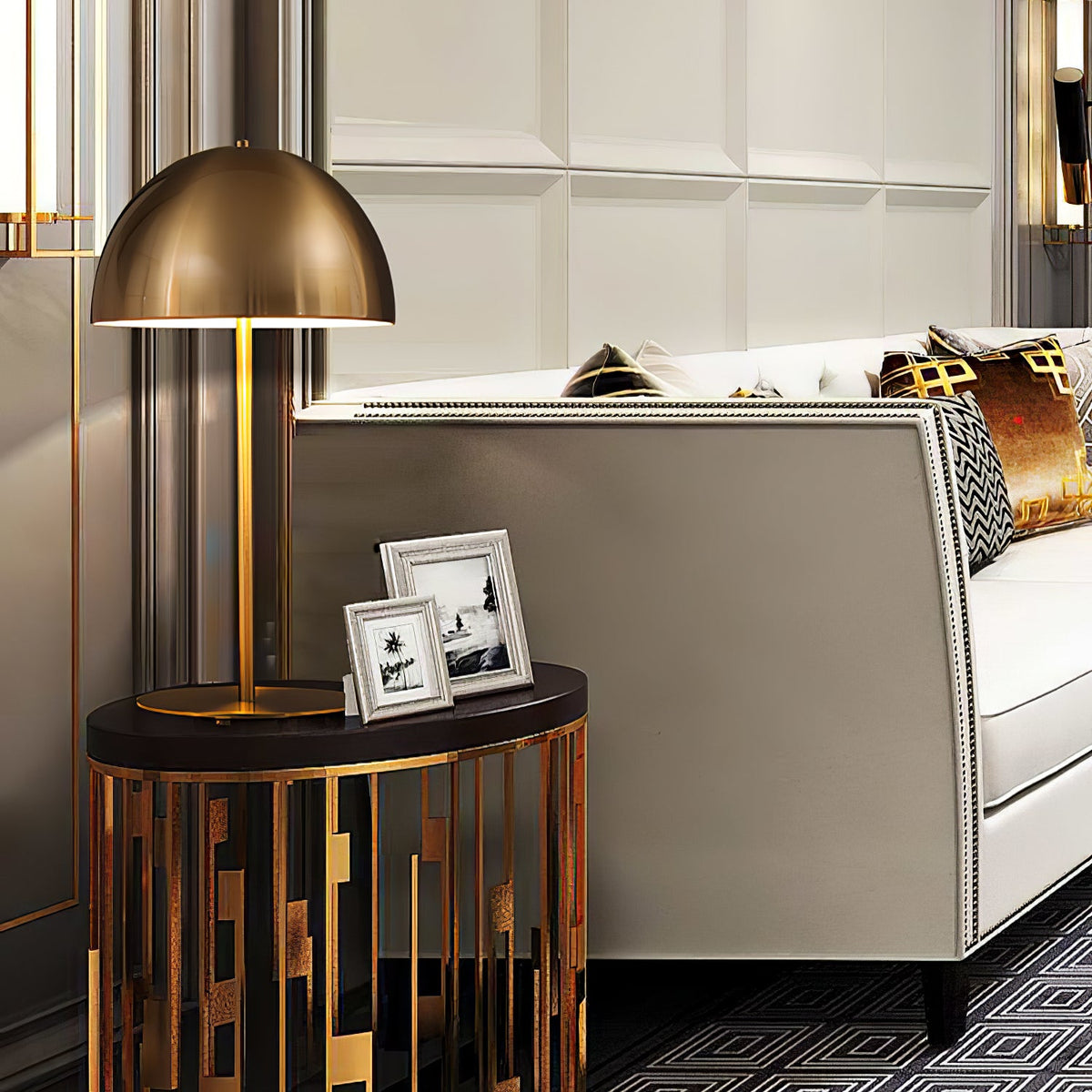Brass dome table lamp from Clérachic on a round side table with framed photos, beside a cream sofa and gold cushions.