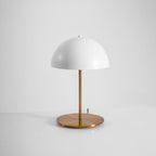 Angled view of a white dome table lamp from Clérachic with a copper-toned brass base, on a pale studio background.