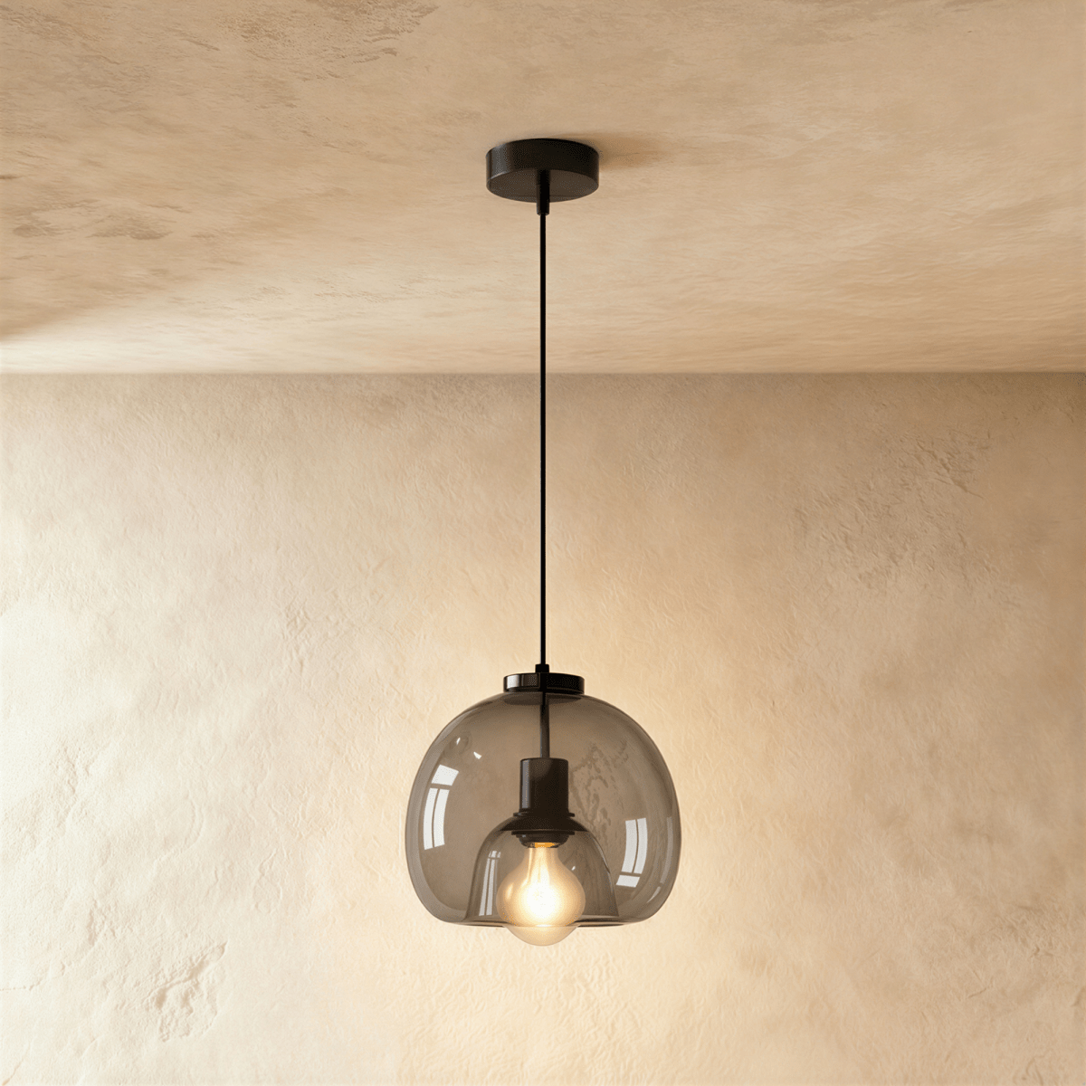 Clérachic single pendant with a smoked glass shade, a black cord and ceiling rose, its filament bulb lit against limewash.