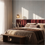 Clérachic smoked glass pendant glowing over a bedroom with a burgundy upholstered headboard and panelled wall.