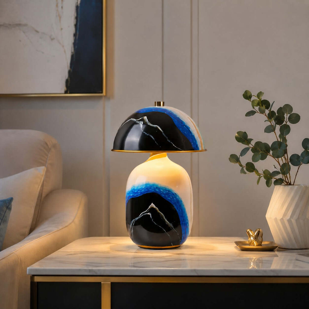 This Clérachic table lamp on a marble-topped side table beside a cream armchair, with eucalyptus in a ridged vase and a small gold dish.