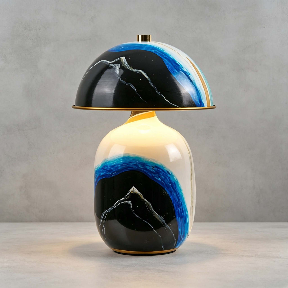Close view of the glossy painted ceramic base and black dome of this Clérachic table lamp on a grey stone surface and plain backdrop.