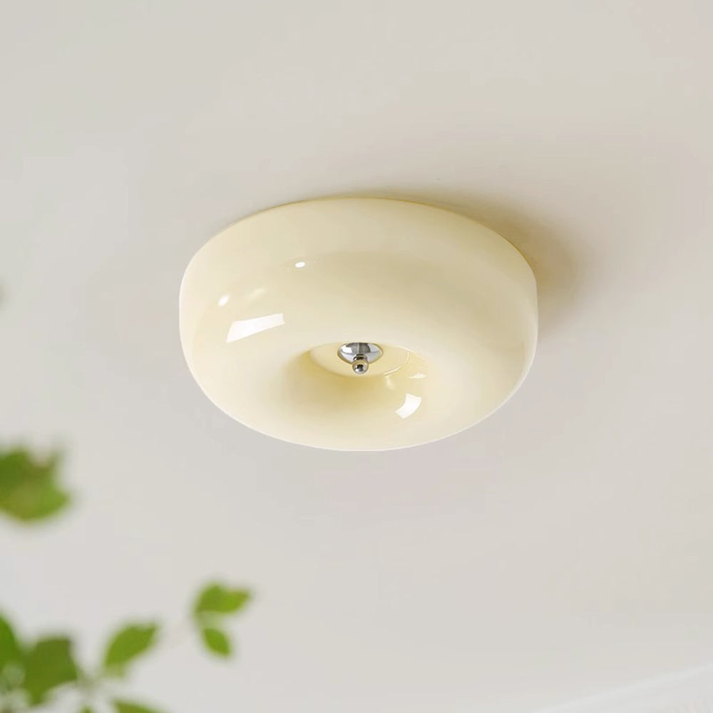 Angled view of the Clérachic Domed Glass Ceiling Light on a pale ceiling, the opal glass reading soft cream-ivory beside green leaves.