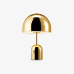 This Clérachic gold table lamp is shown lit, its dome shade glowing softly against a plain background.