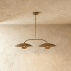 Clérachic chandelier in vintage brass, two dome shades hung from an angled bar with a central rod.