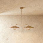 Clérachic chandelier in a warm satin brass finish, twin dome shades suspended from an angled bar.