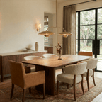 Clérachic chandelier in brass over a dining table with a bronze dancer figurine and garden doors.