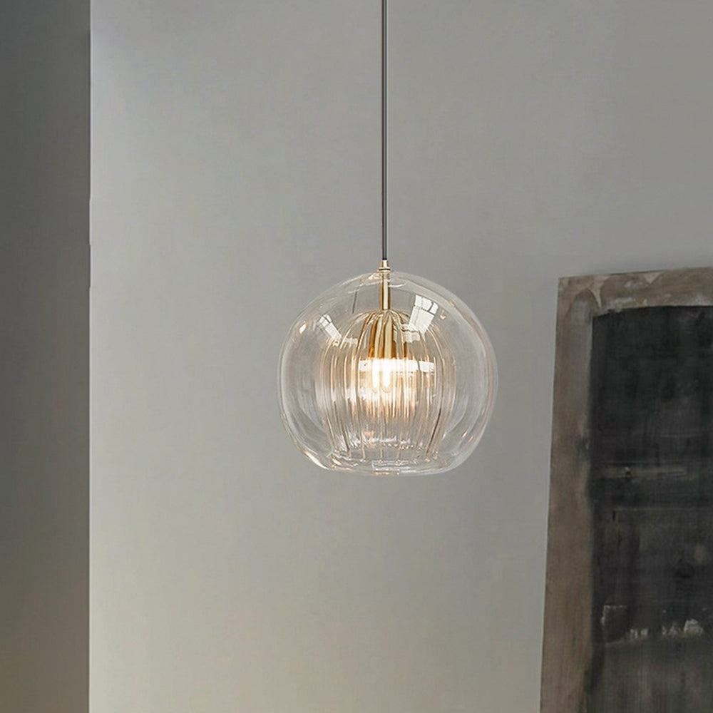 Clérachic double-wall globe pendant light in clear glass, lit against a pale plaster wall beside a framed canvas in a quiet hallway.