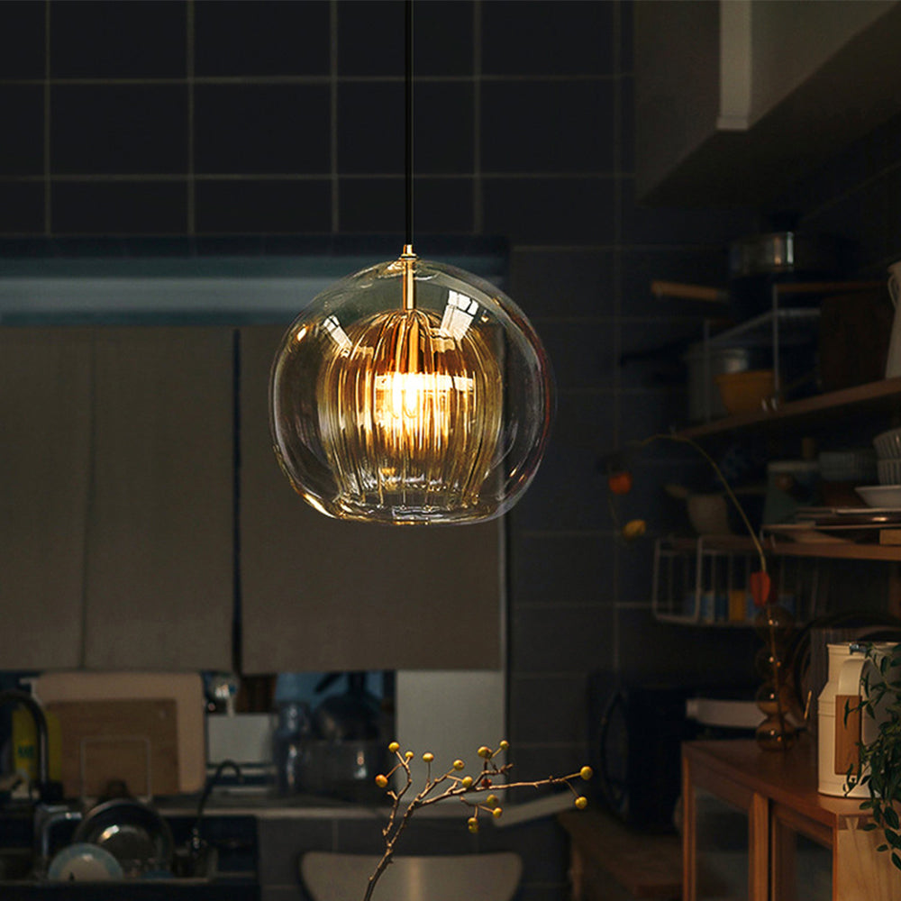 Clérachic double-wall globe pendant lit over a dark-tiled kitchen at night, the fluted inner shade throwing warm bands of light.