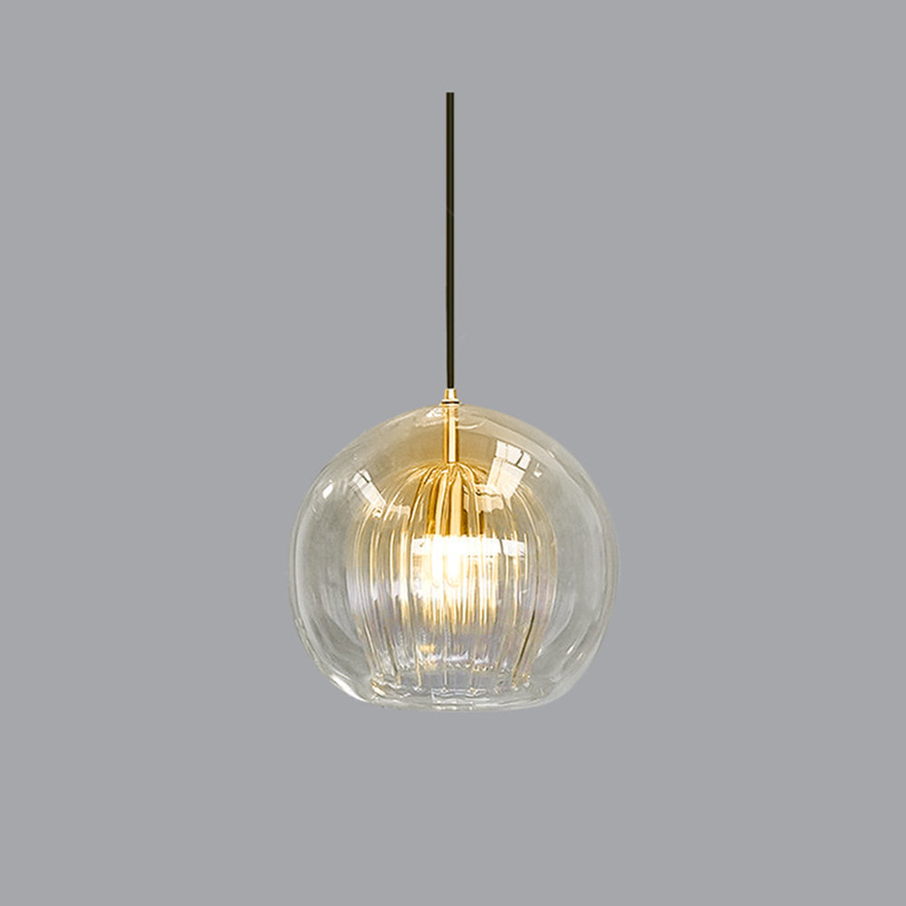 Angled studio view of the Clérachic double-wall globe pendant, the warm gold cast of the brass holder showing through the clear glass.