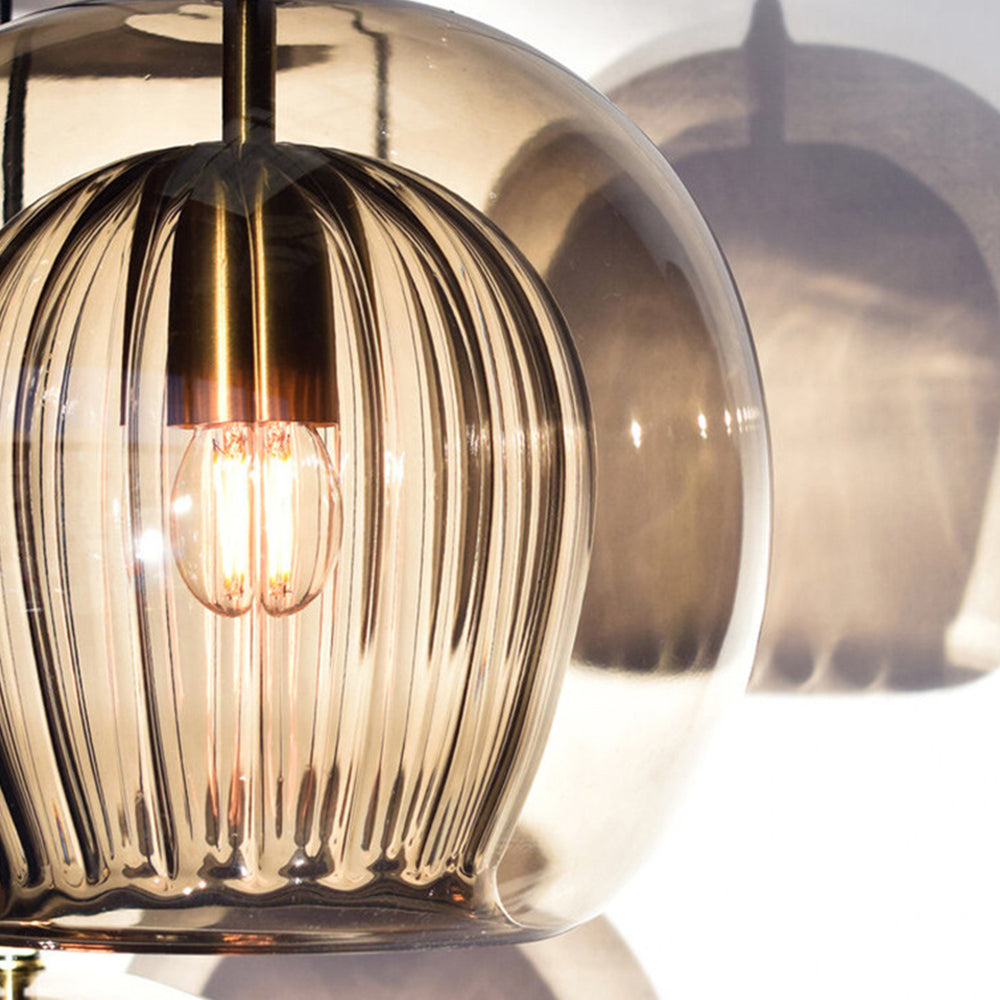 Close-up of the amber Clérachic double-wall globe pendant, its ribbed inner shade casting striped shadows across a sunlit wall.