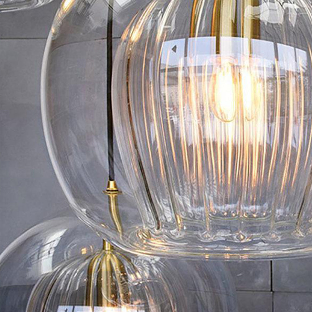 Detail of three clear Clérachic double-wall globe pendants overlapping, a lit filament seen through the fluted inner cylinder.