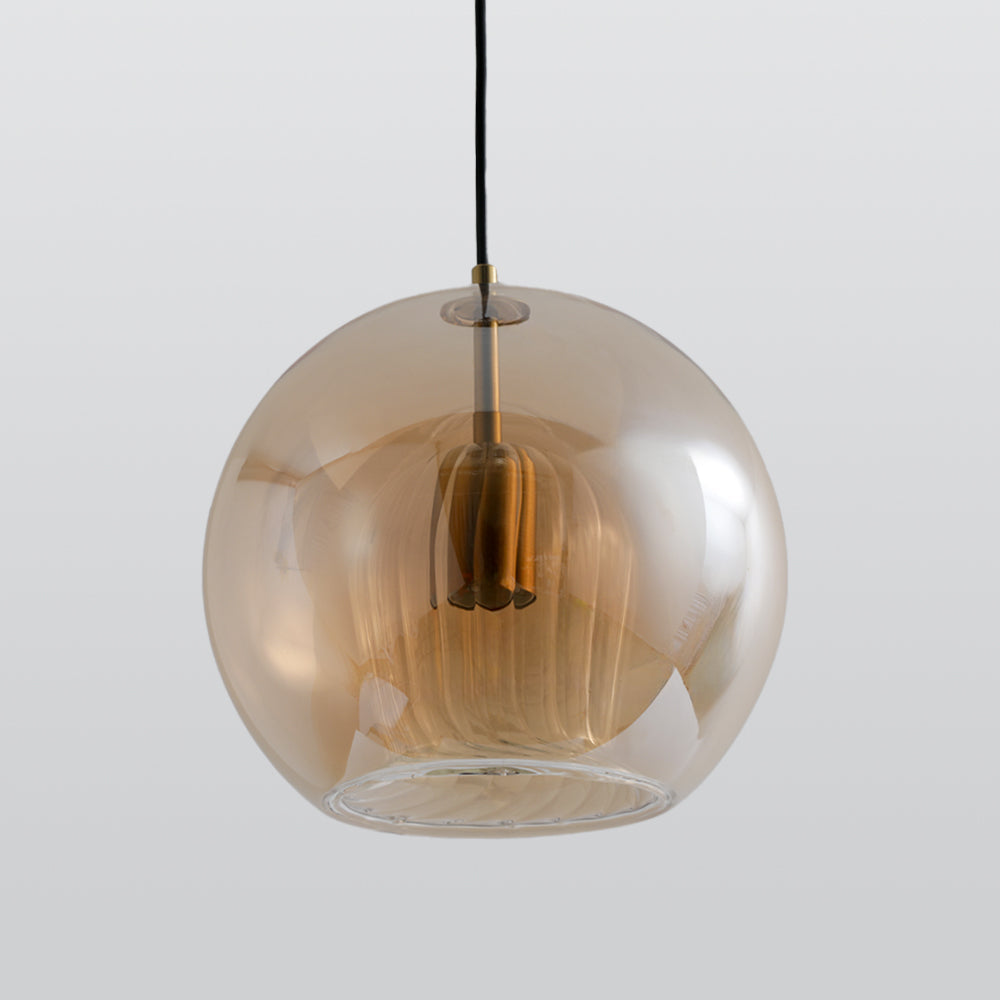 Amber Clérachic double-wall globe pendant seen from just below, the fluted inner shade suspended inside the deep honey outer sphere.