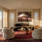 This Clérachic sculptural pendant hangs above a plush living room seating group with a warm red patterned rug.