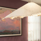 Detail of the Clérachic pendant's textured surface and torn fabric-like hem glowing against a plum dining wall.