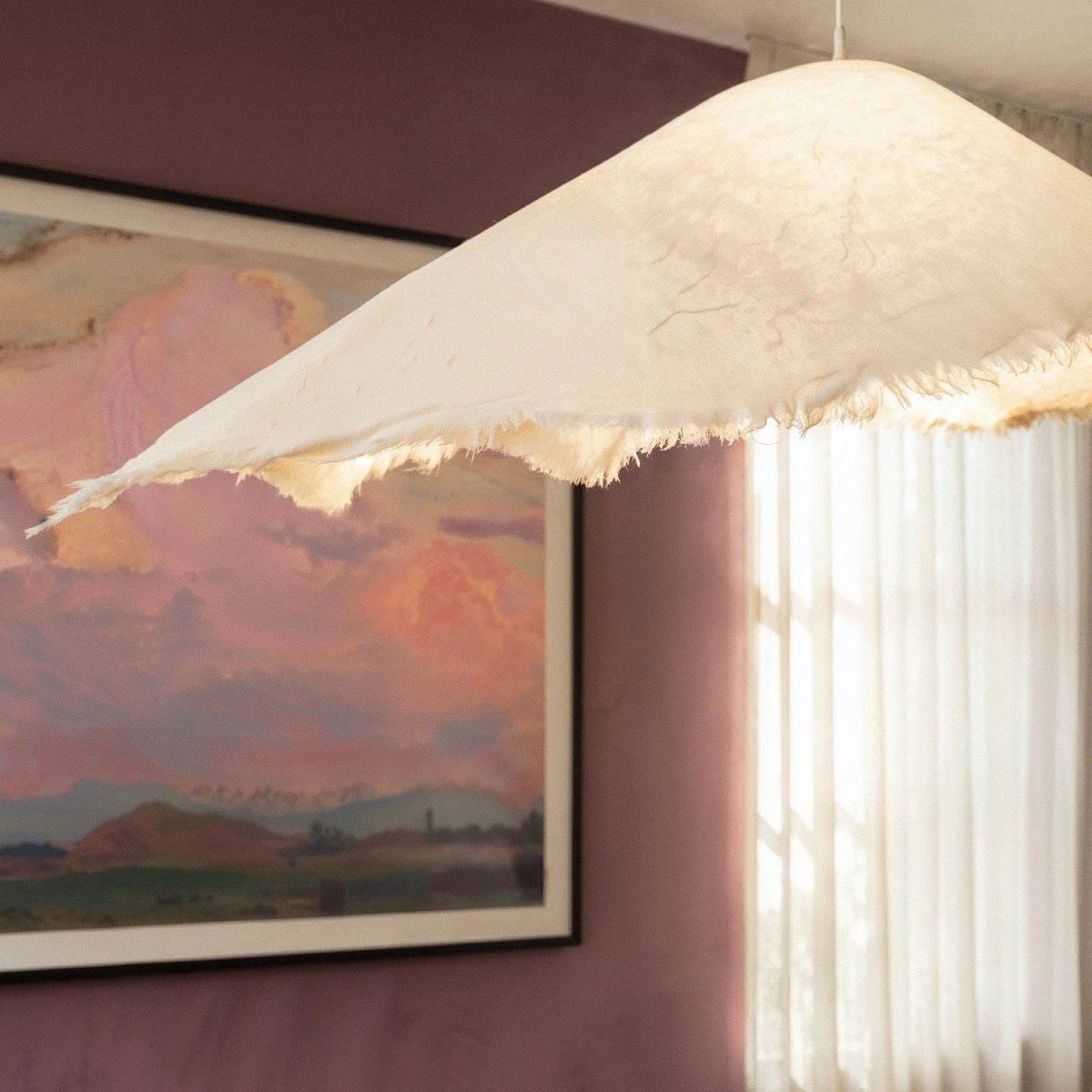 Detail of the Clérachic pendant's textured surface and torn fabric-like hem glowing against a plum dining wall.